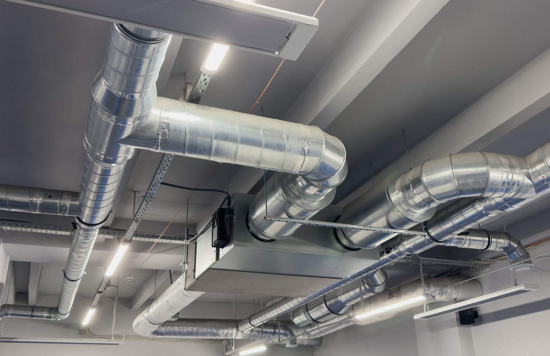 Metal pipes in thermal insulation winding on the ceiling of an industrial enterprise.